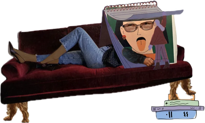 Understanding lounges on a red velvet couch, face hidden behind an open spiral notebook, with a stack of books beside the couch.